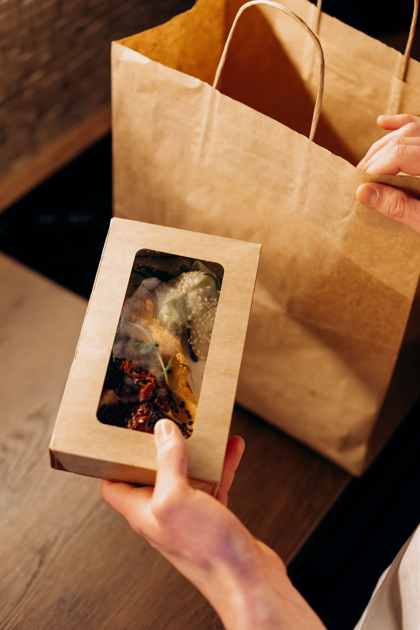 Manos sosteniendo un envase de comida listo para llevar