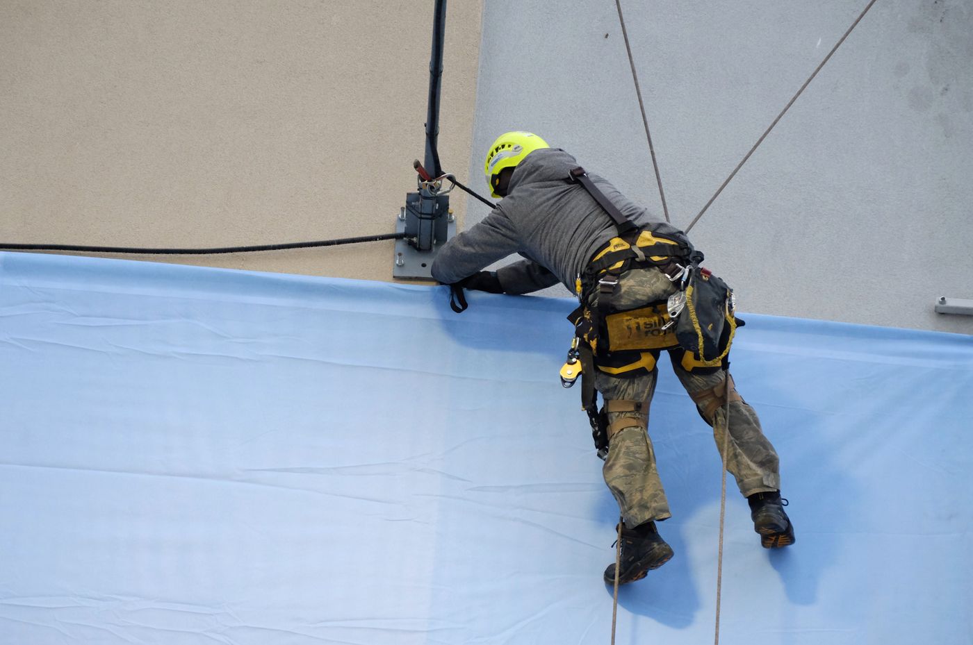 Técnico trabajando con equipo de seguridad en la fachada de un edificio
