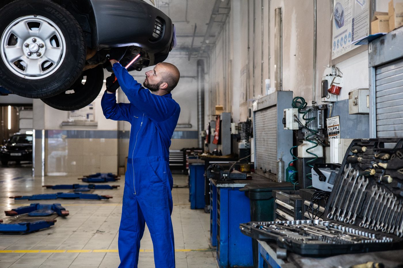 Mecánico inspeccionando un vehículo elevado dentro de un taller